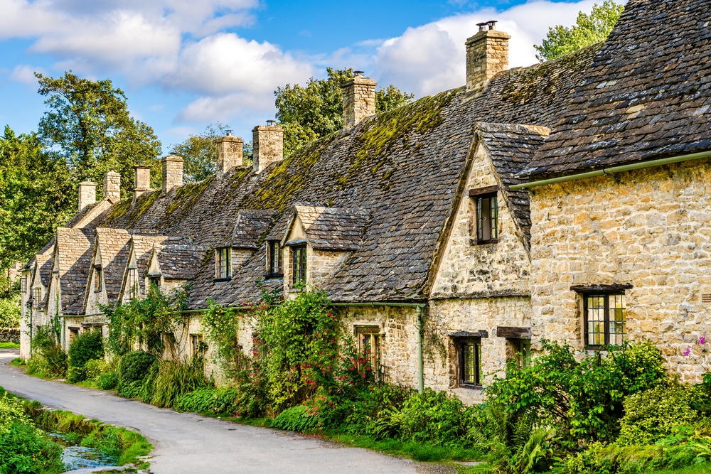 a row of stone home lined up on a road in england, one of the best things to do in europe