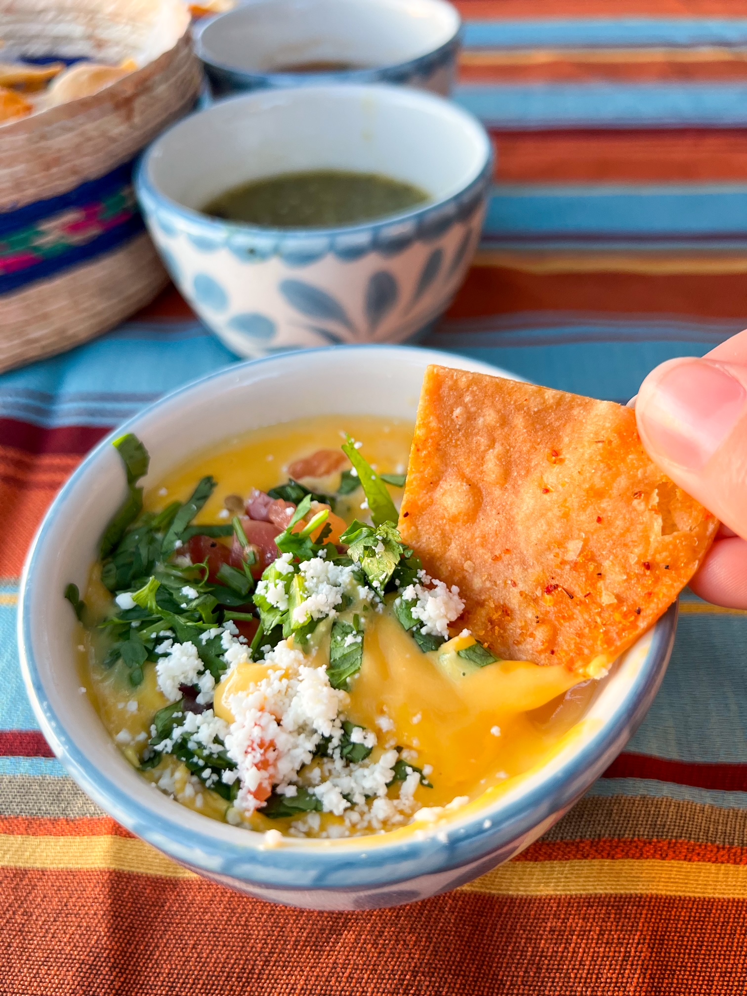 woman dipping her hand into queso