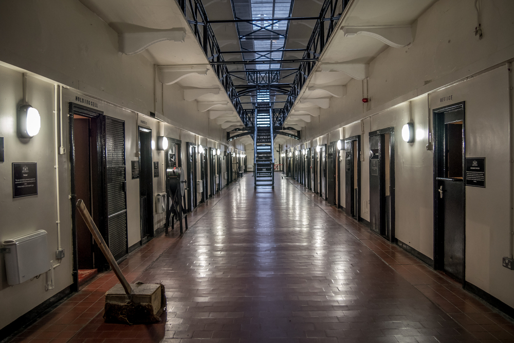 Photo of the inside of Crumlin Road Gaol, one of the most popular things to do in northern ireland. The photo shows a long white hallway with jail cells on both sides. 