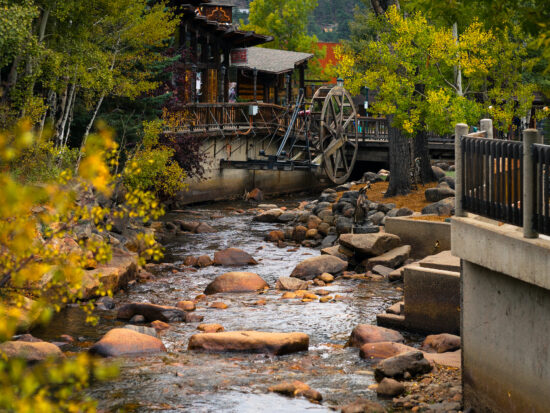 wooden homes of Estes Park along rocky stream