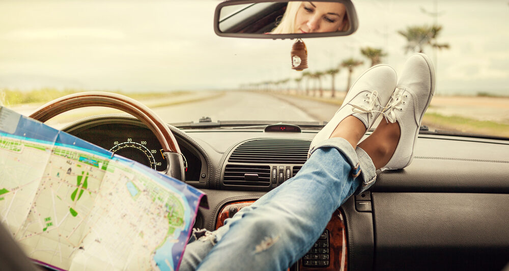 Girl with feet on dashboard of a car in an article about road trip questions
