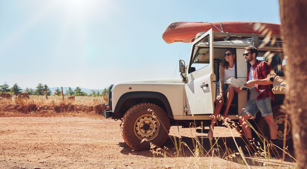 A young couple near a jeep in an article about deep road trip questions