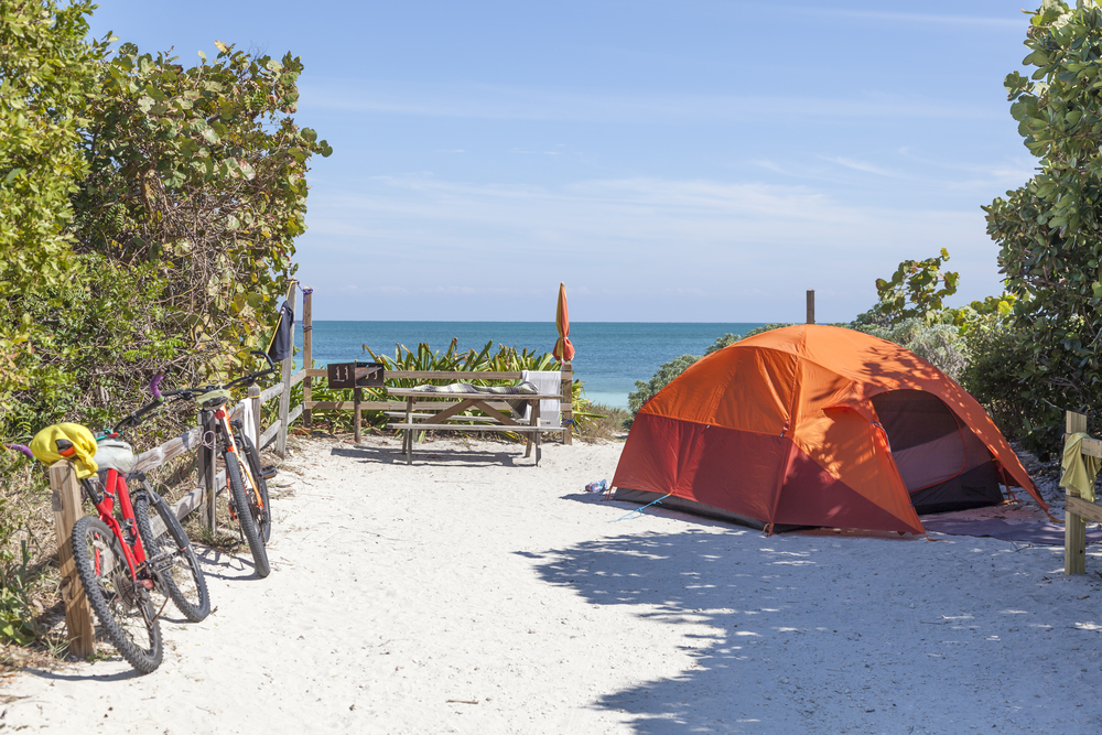 An orange tent and bikes sit on the beach in Key West, Florida, which is one of the top locations for best beach camping in the USA.