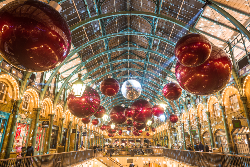 Inside Covent Garden lit up with Christmas lights and giant hanging ornaments.