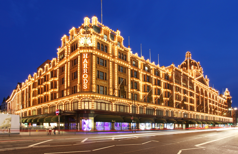 Lit up exterior of Harrods at dusk during winter in London.