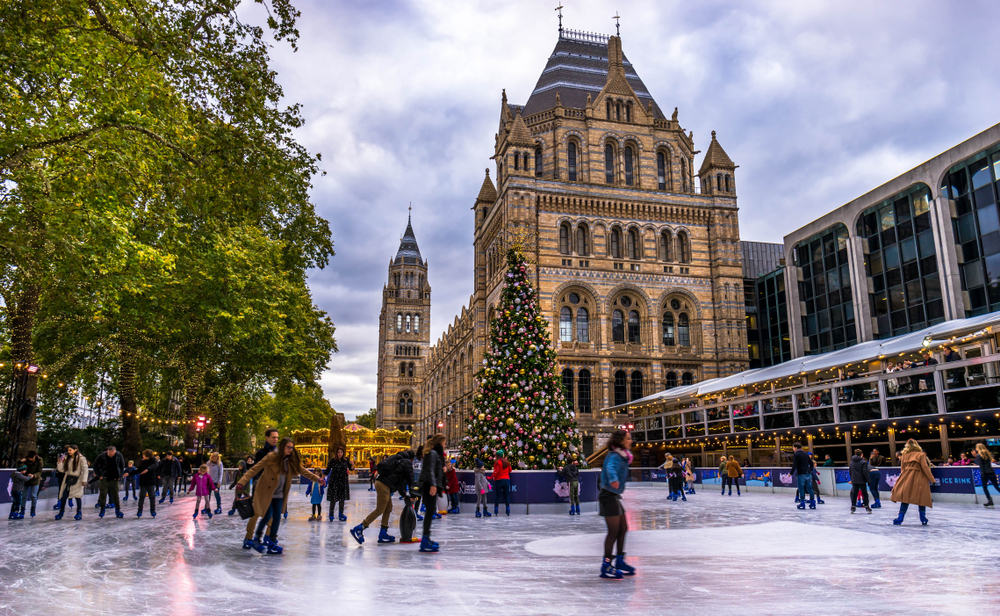 People ice skating around a Christmas tree next to the Natural History Museum.
