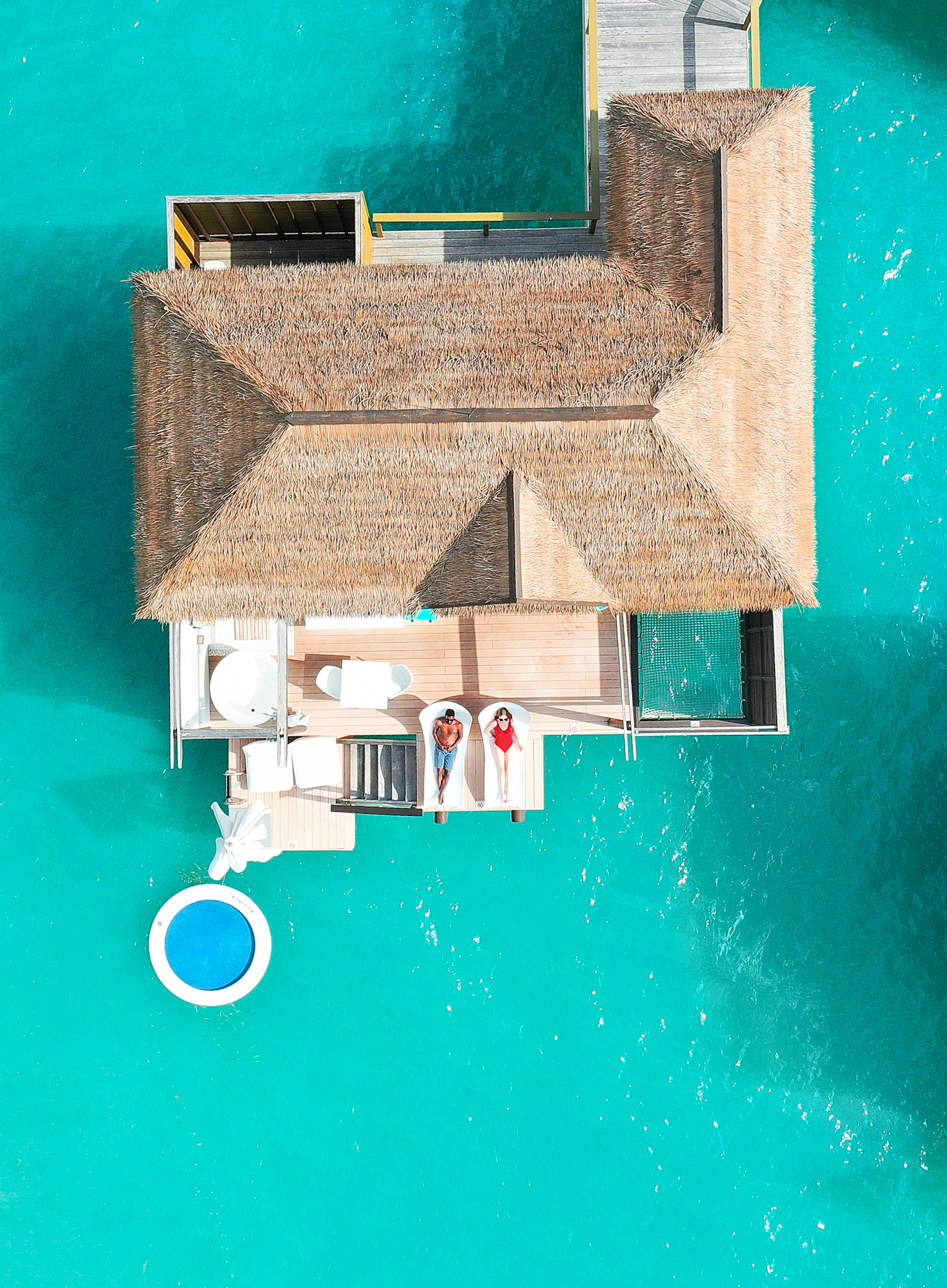 couple on the deck of an overwater bungalow in an all-inclusive resort. 