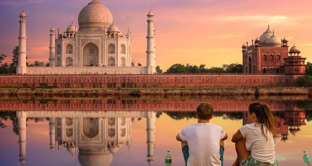 couple sitting in front of the taj mahal in india