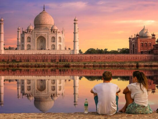 couple sitting in front of the taj mahal in india