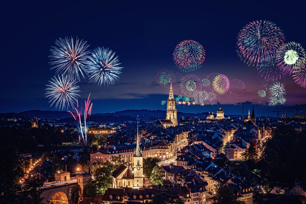 An arial shot of Zurich, Christmas cities in Europe, shows the city abright with Christmas lights and fireworks bursting in the sky, celebrating. 