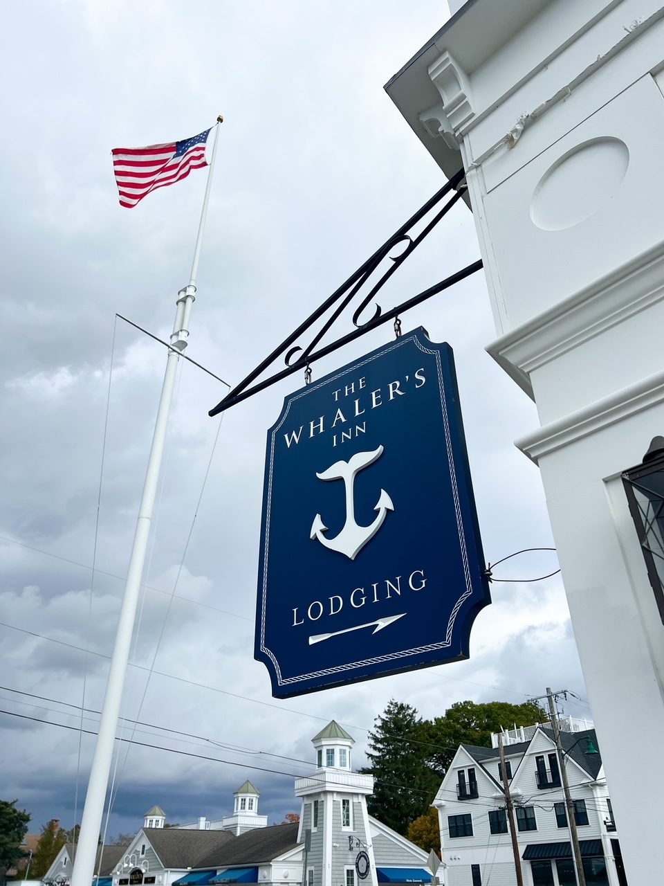 A close up of the Whaler's Inn sign points guests to the lodging in Downton mystic that is close to everything: the blue sign, white lettering and anchor are truly coastal. 