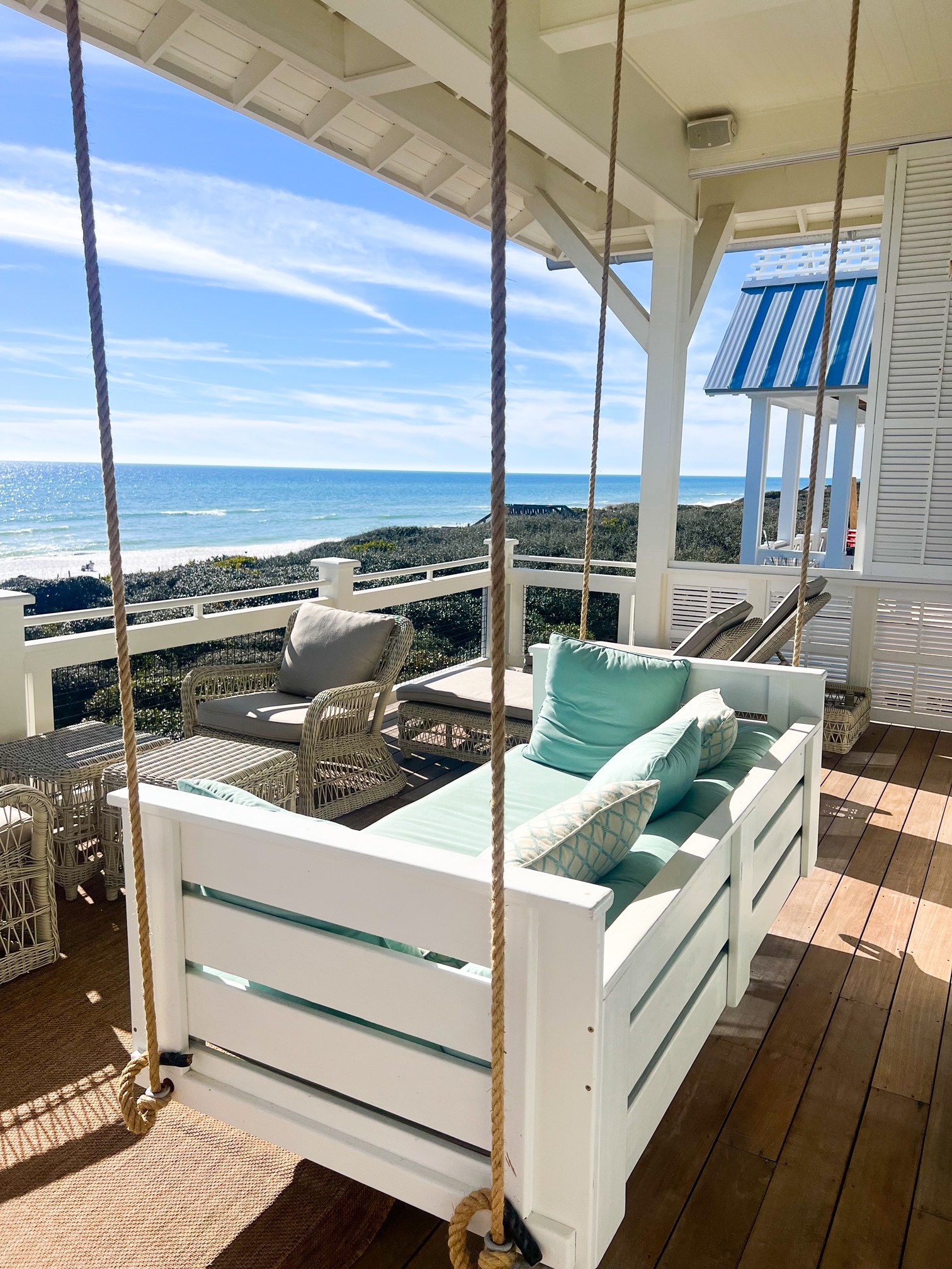 a porch swing under a covered patio overlooking the ocean