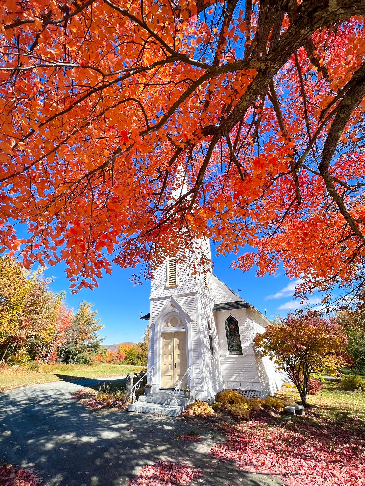 The leaves of a tree sit in the right corner of this photo, covering the top of St. Matthews Chapel, which is a must see during your New England Fall Foliage Road Trip Itinerary. 