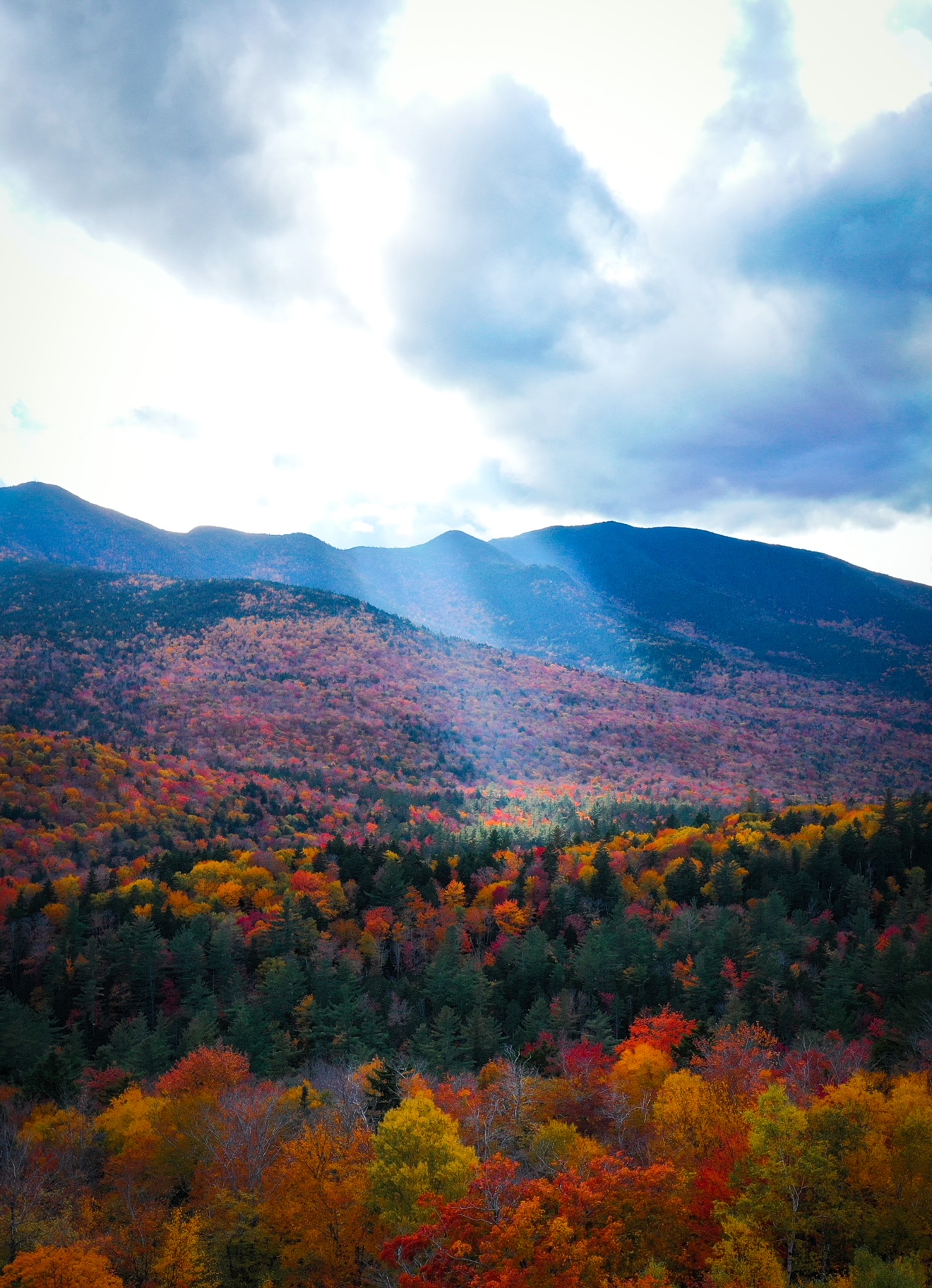 Hancock overlook offers views of the mountains and the surrounding trees: this photo has a streak of light that highlights the golden trees, making this a must see during your New England Fall Foliage Road Trip Itinerary. 