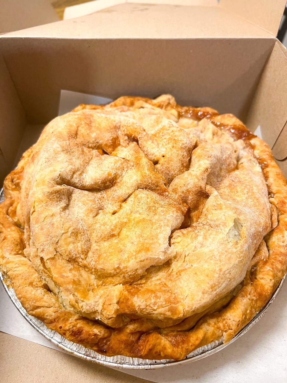 A close up of the Apple Pie at Lost Acres Orchard show site perfectly cooked crust and apple filling spilling out on the side: you have to add Lost Acres to your New England Fall Foliage Road Trip Itinerary. 