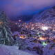 Down a snow capped mountain, featuring many fir trees, sits one of the best Christmas towns in Europe: Zermatt: this town is nestled between rolling landscapes and is aglow with festive lights at night.