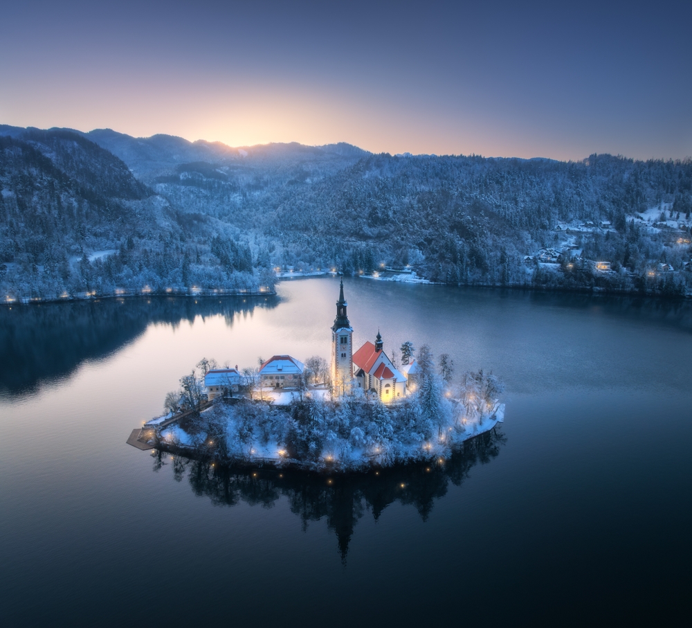 An arial shot of Lake Bled shows the Christmas town in the center of the lake a glow with lights, and the chapel is specifically light up, making it one of the best Christmas towns in Europe. 