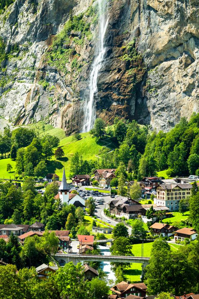 large waterfall in background, village in middle and bottom of image