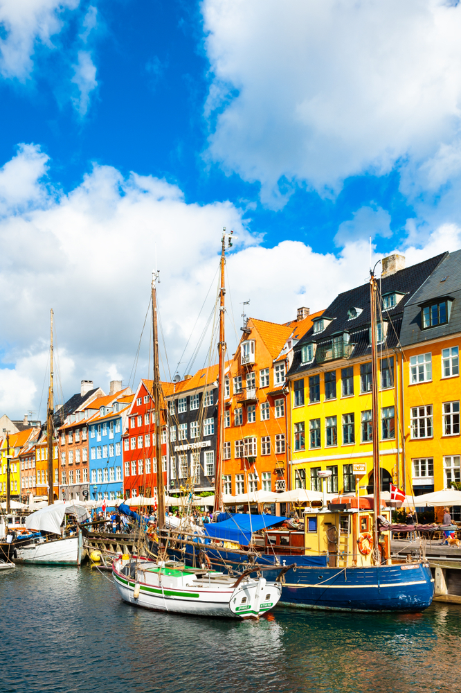 boats are docked in the water in front of a row of colorful buildings in Copenhagen, one of the best things to do in europe