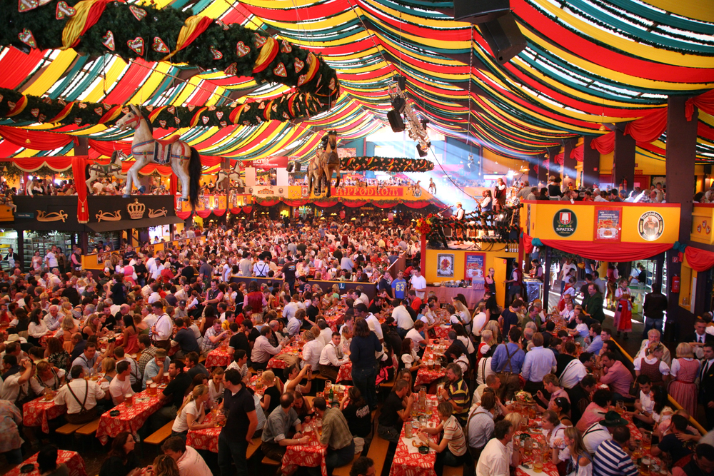 the inside of a large tent at munich oktoberfest, many people are sitting inside at table drinking beer 