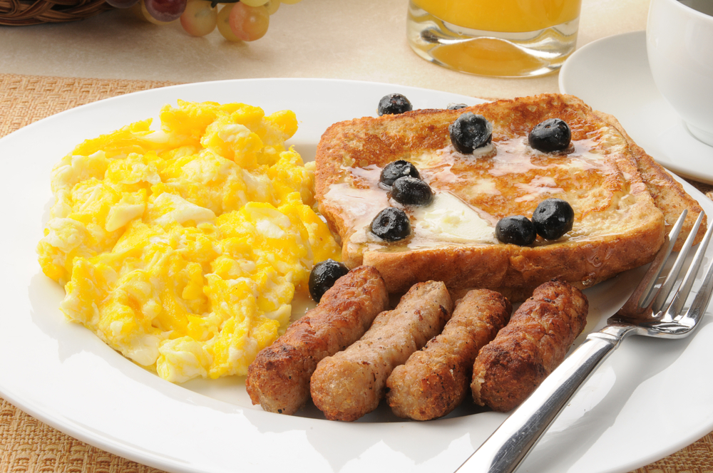 Breakfast is always yummy: a plate of yellow eggs, sausage and blueberry French toast looks appetizing. 