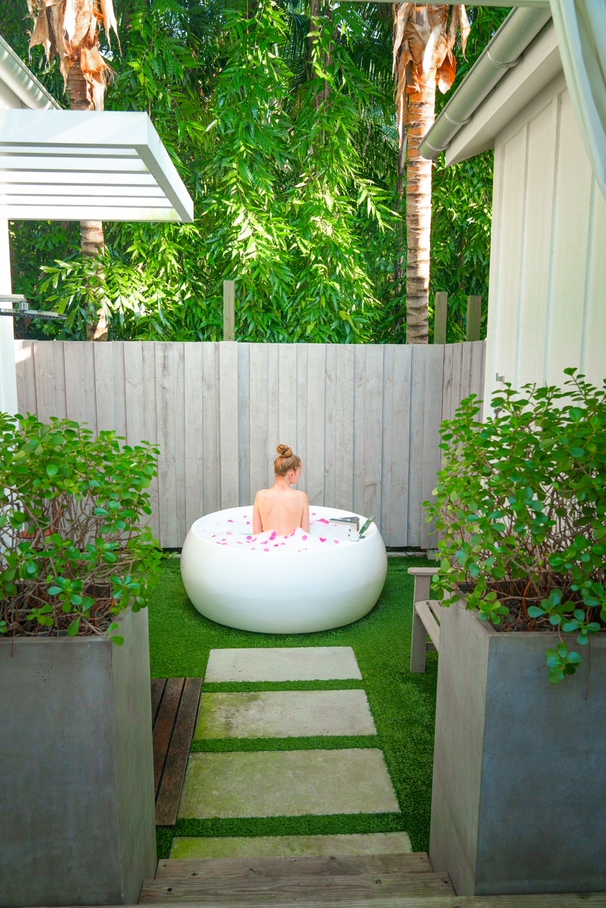 A gir in the outdoor bath in the private garden are of the bungalows with rose petals in the water