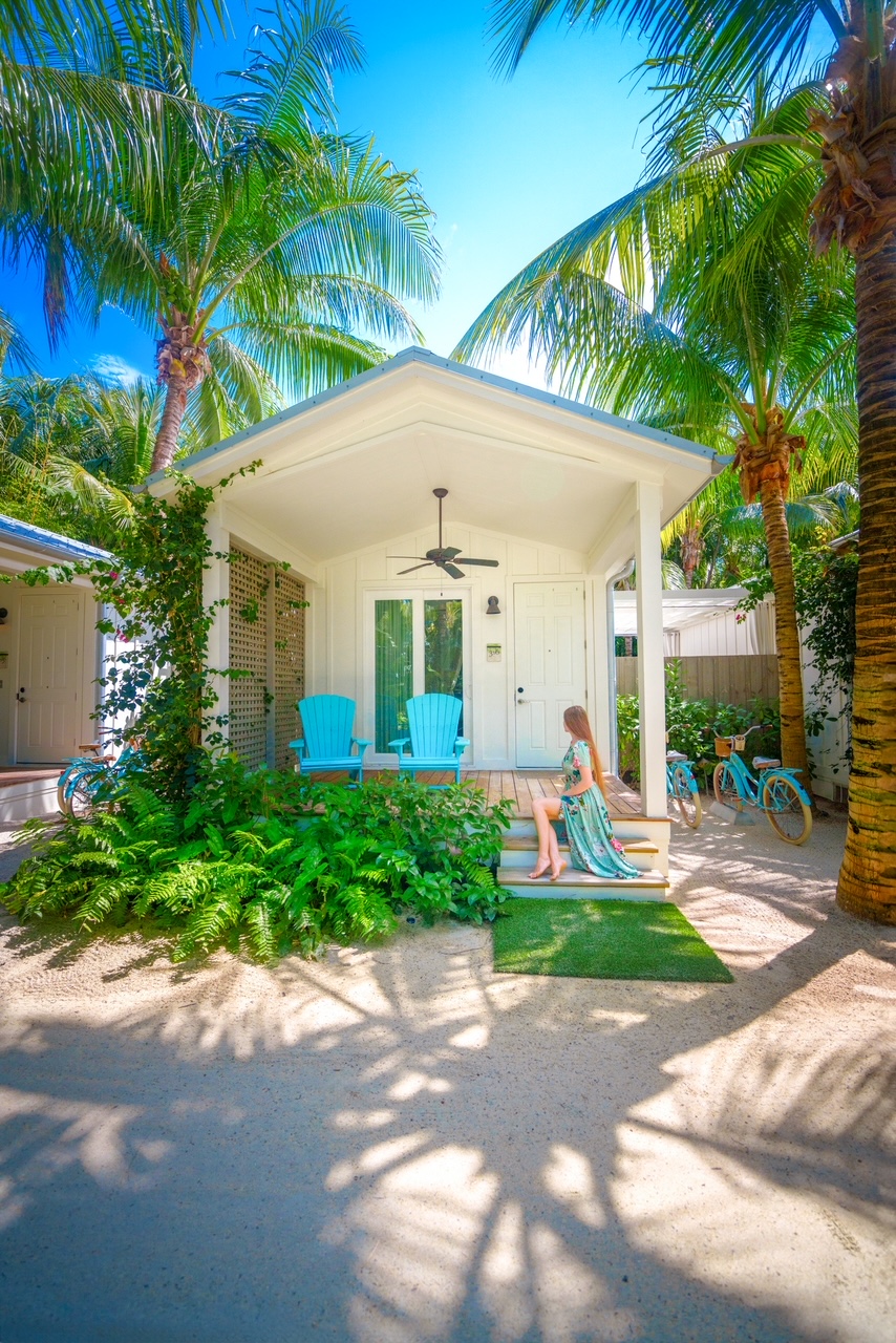 a girl in a dress sitting on the front porch of the garden bungalow