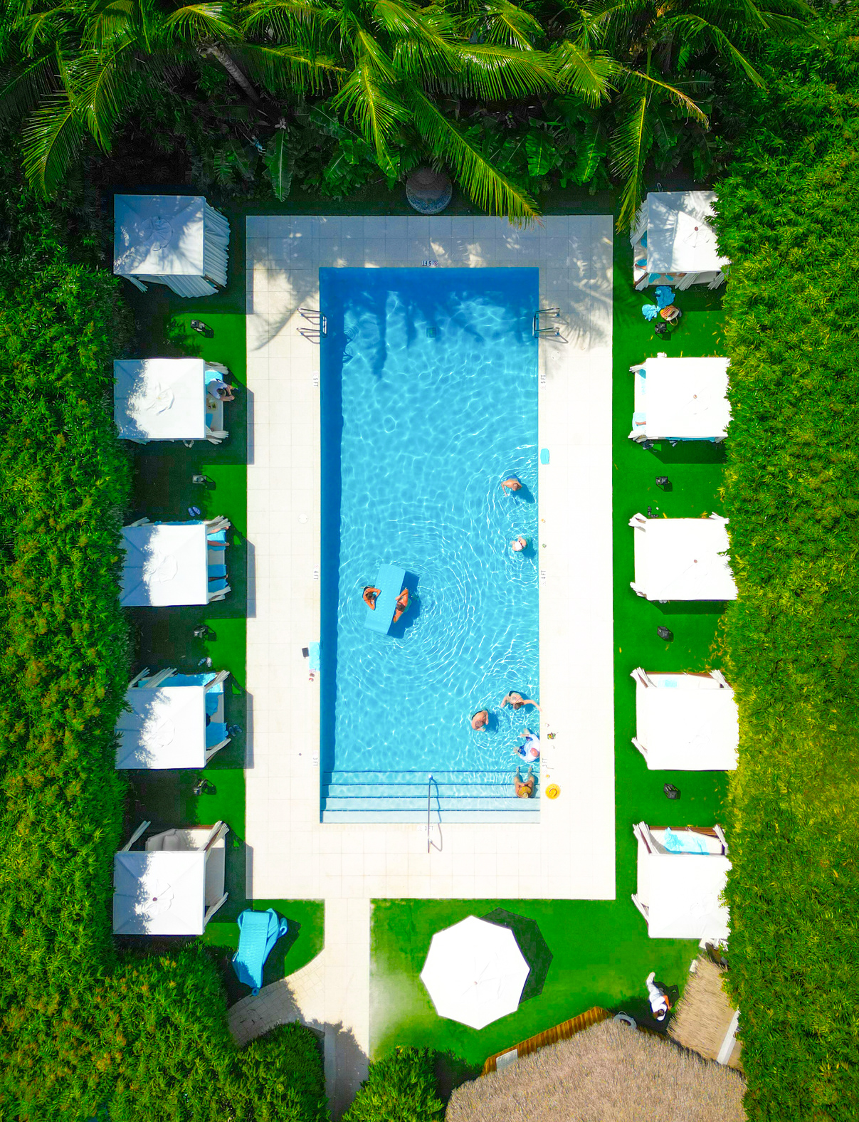 the zen pool is surrounded buy cabanas and lush green foliage and crystal clear water