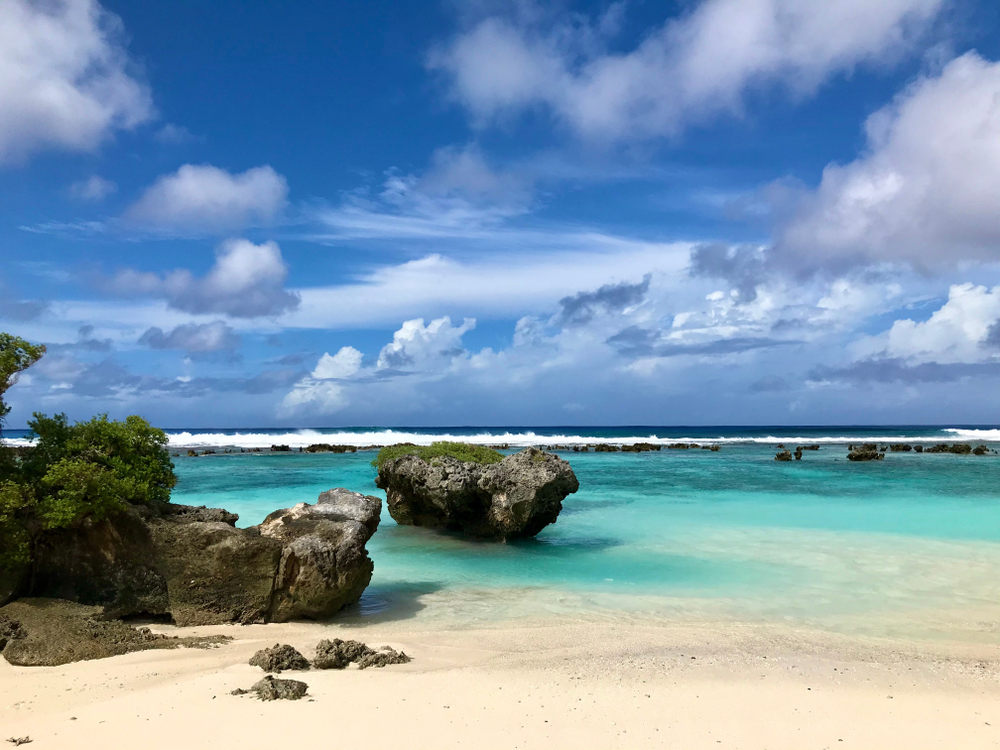 Rota lsland Northern Mariana Island. You can see the sea, sand and several rocks on the coastline. One of the  Islands USA citizens can visit without a passport. 