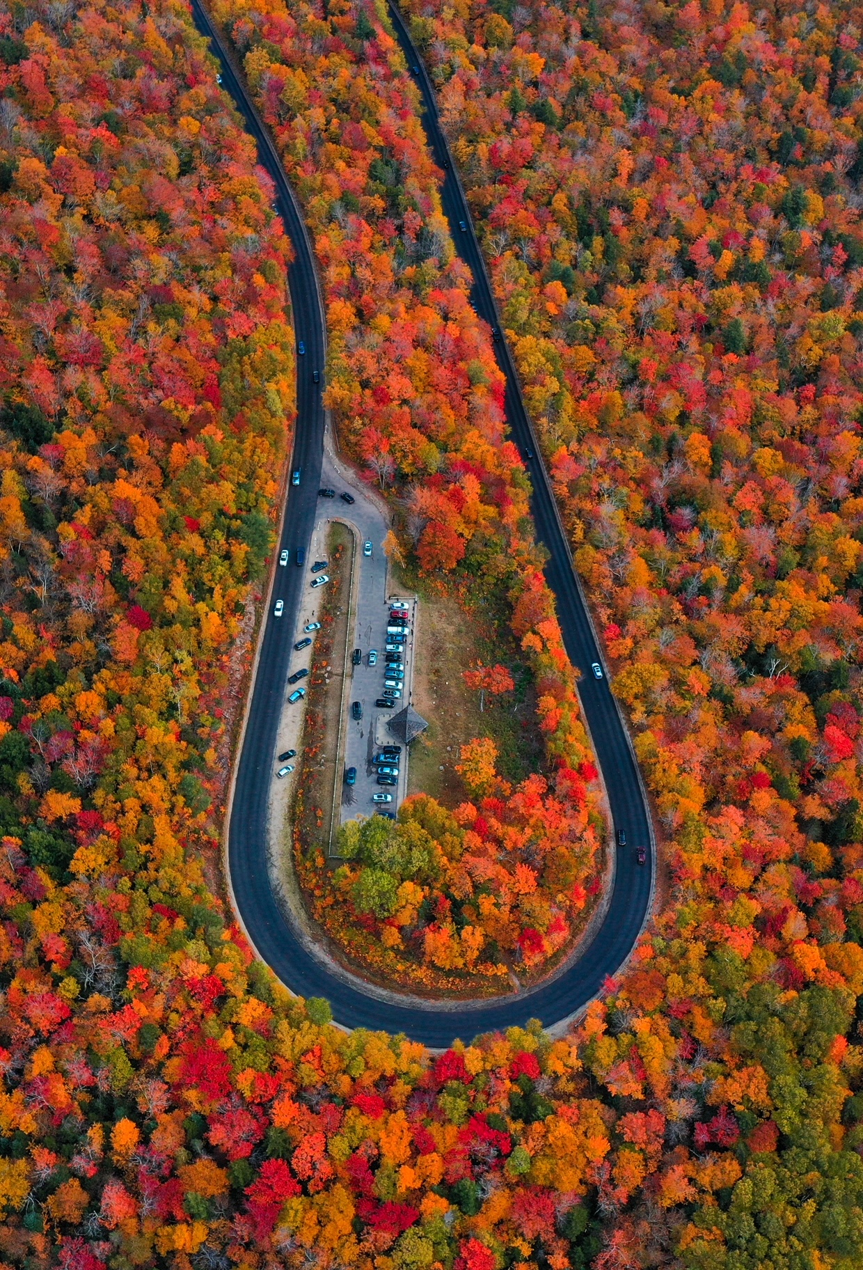 An overhead shot shows the winding loop of Kancamagus Highway in New Hampshire, but it also shows the vibrant reds and oranges of the fall foliage. 