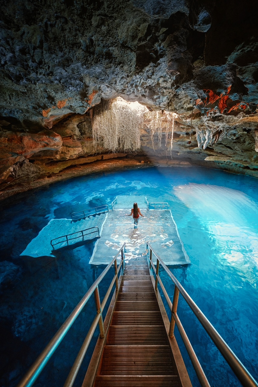 Of all the prettiest states in the USA, Florida is one of them, as shown in this photo as a women in a red bathing suit cascades down stairs into a cave that features crystal clear water, where the spring is underground! 