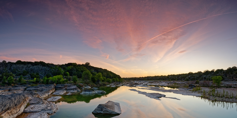 A cotton candy sunset with pinks and blues over over the lakes and rocks of an inland area in Texas, which is surprisingly one of the prettiest states in the USA! 