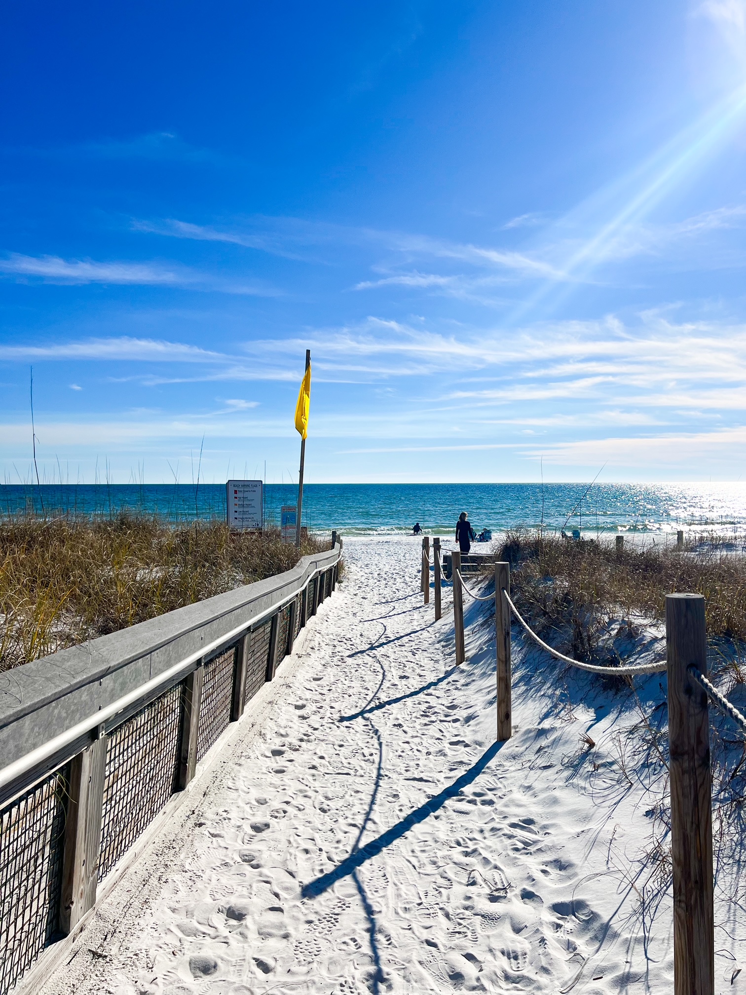 the wooden boardwalk leading down to the sandy beach of Grayton with yellow flag