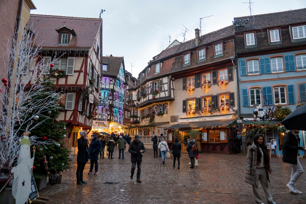 people walking through the stone streets in the fairytale village of colmar france 