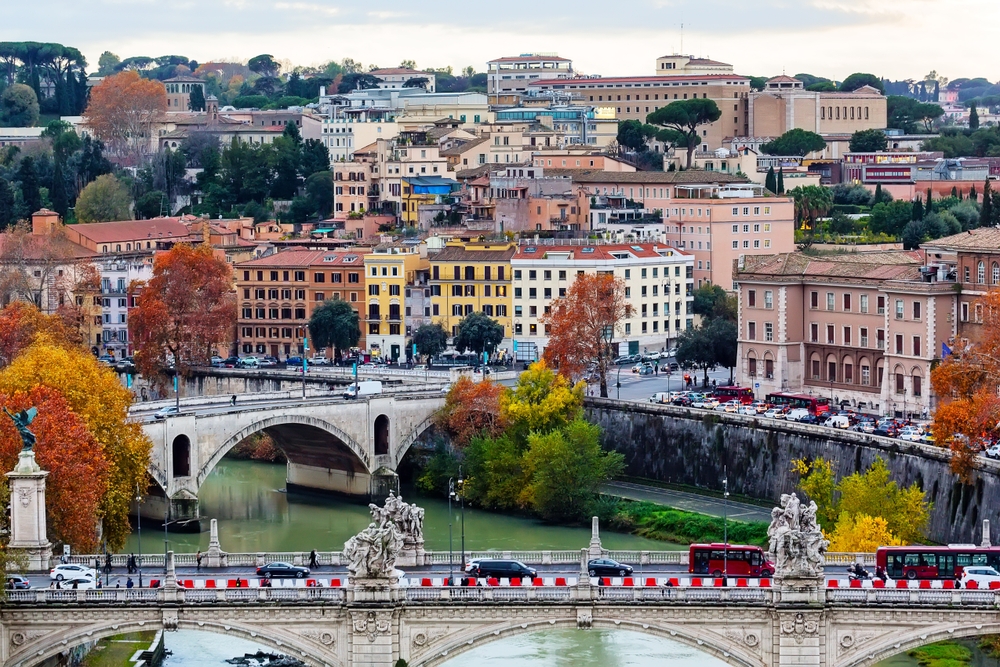 aerial photo of two bridges crossing  a river in front of a city in autumn