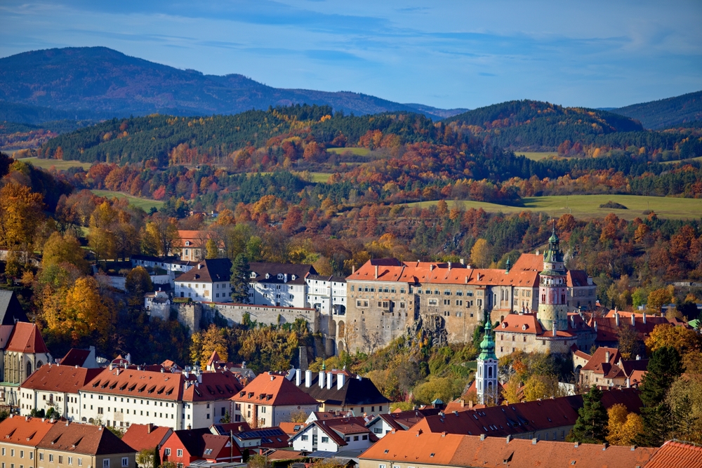 one of the best places to visit in europe in november, cesky krumlov, aerial photo of historic buildings and rolling hills in the background in november 