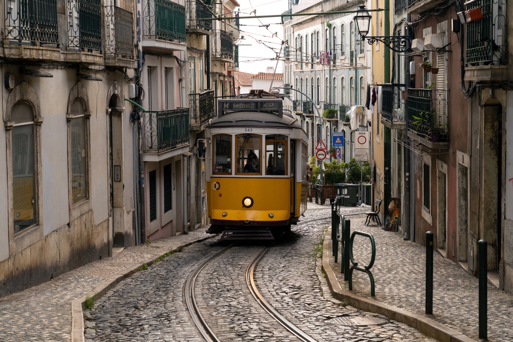 a cable car in lisbon making its way up the cobblestone road between buildings 