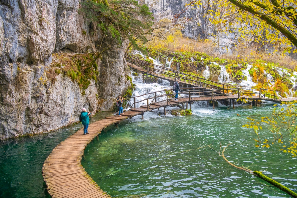 wooden boardwalk over water in plitvice lakes national park, people are walking on the boardwalks