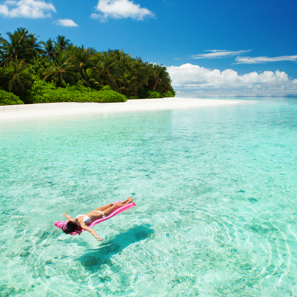 Woman relaxing on inflatable mattress in the sea. The article is about the best time to visit the Maldives