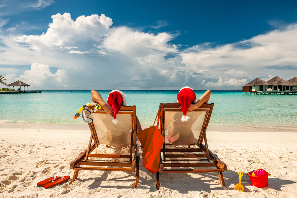 Couple on a tropical beach in Maldives at Christmas with Santa hats on. 