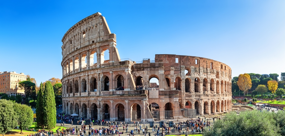 The Colosseum stands tall and crowds gather at the grounds: places like this require booking in advance, and not doing so is one of those mistakes to avoid in Europe.