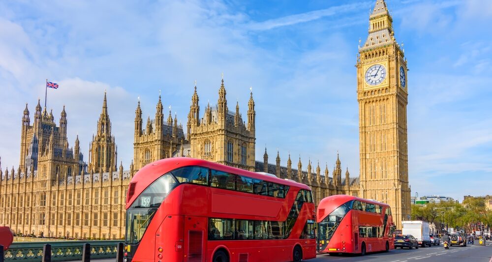 big red bus in london with big ben tower and blue sky