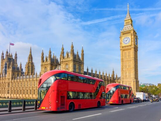 big red bus in london with big ben tower and blue sky