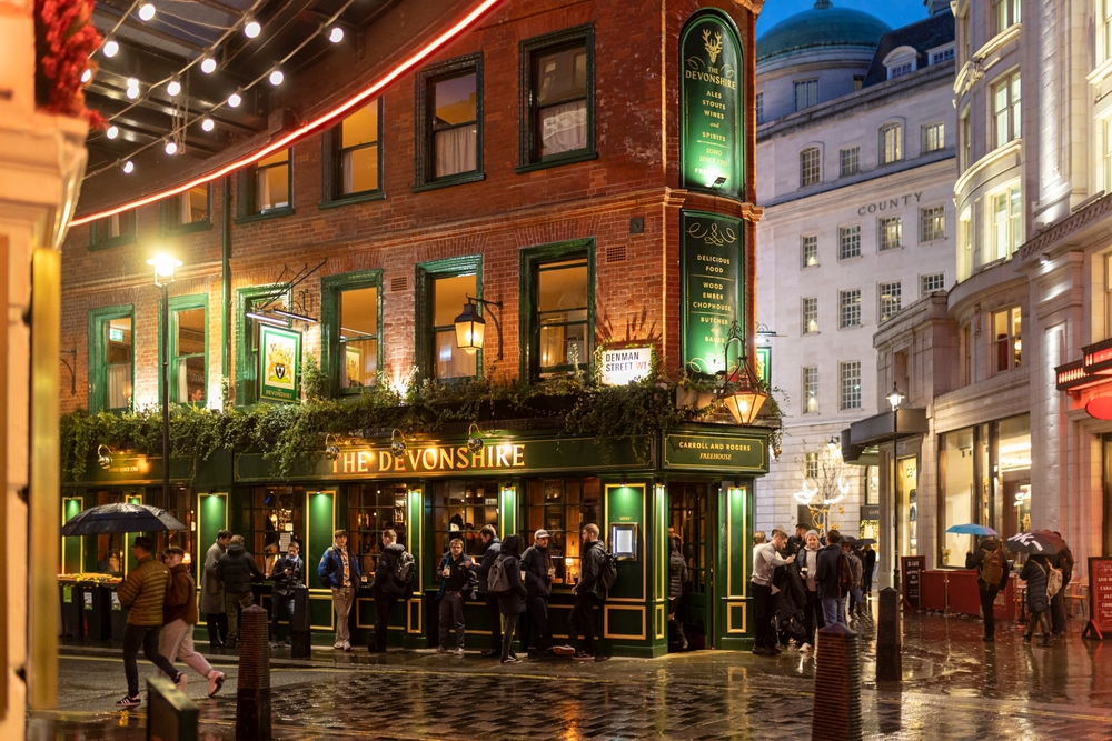 People drinking after work at the Pub "The devonshire" in the rain. People have umbrellas. 