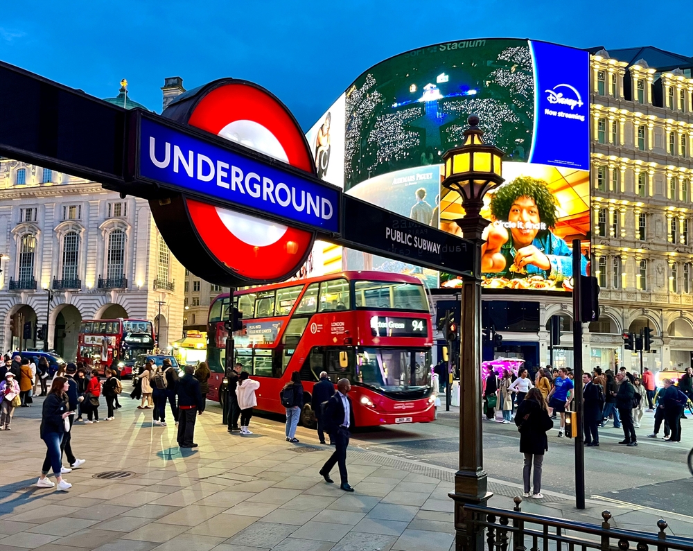 London tube station at Piccadilly Circus. It is dusk and the lights are all on. 