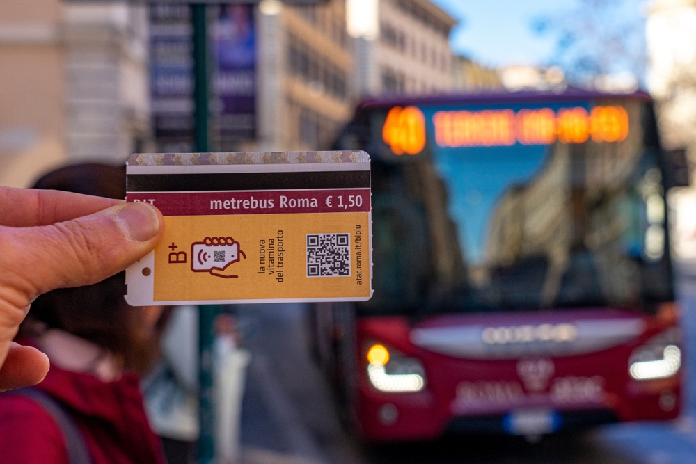 a person holding their bus ticket in front of a bus in Rome