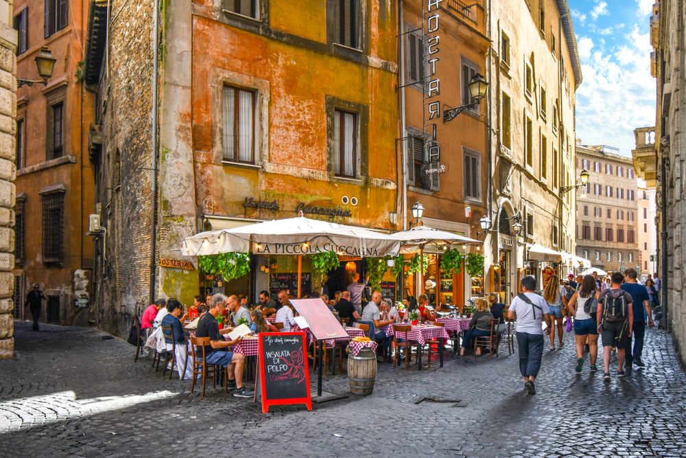 a restaurant with people dining at the outdoor seating on the street in Rome