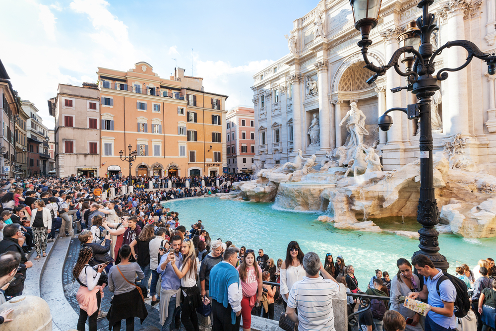 a large crowd of people packed together at the Trevi Fountain