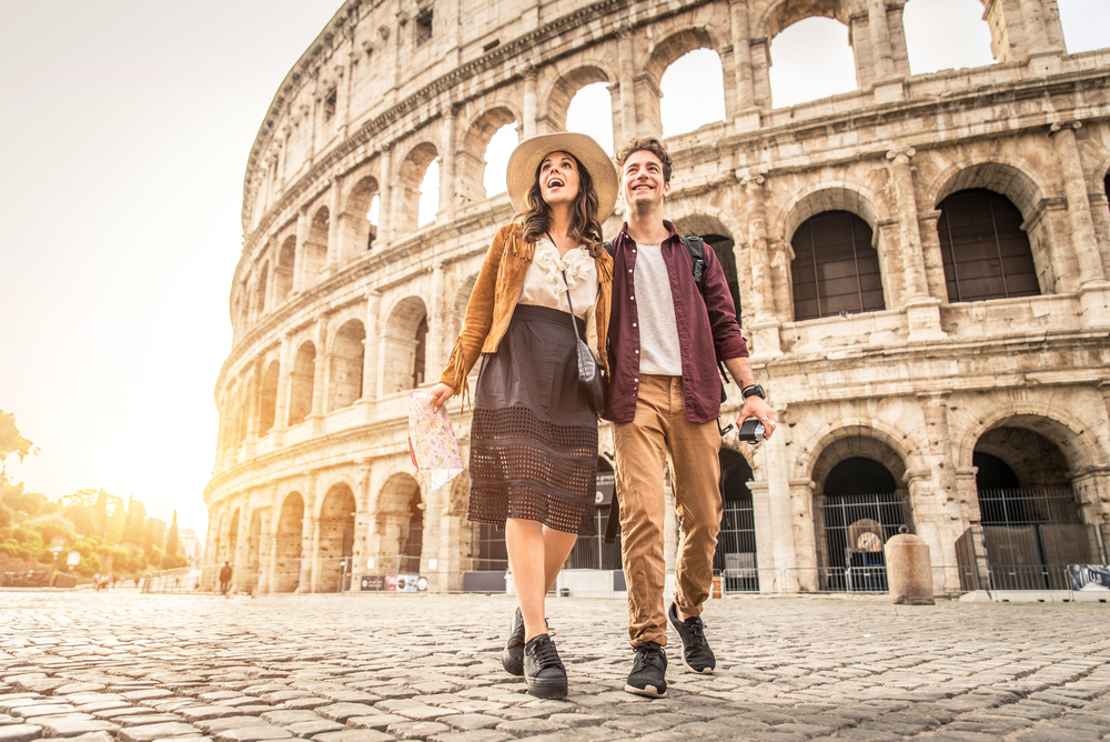 two tourists walking in tennis shoes in front of the Colosseum