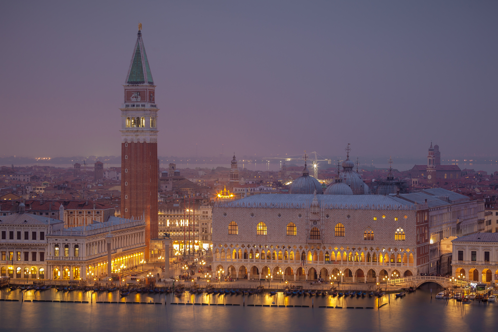 Venice at night during the winter has a warm, yellow hue with its golden lights and snow-capped buildings. 